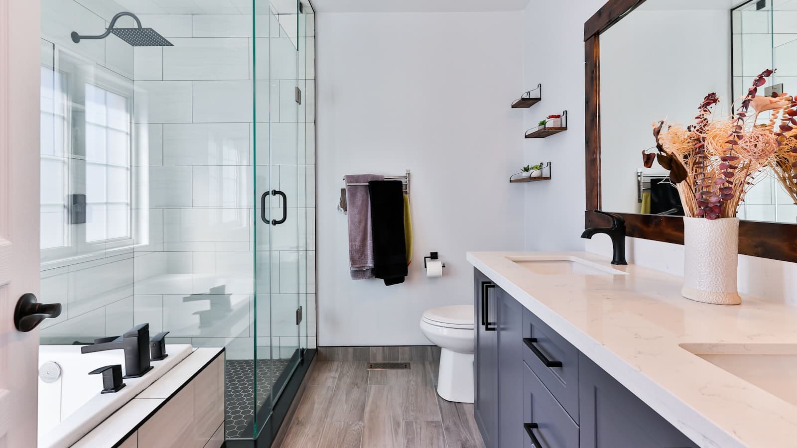A modern remodeled bathroom with a glass-enclosed shower, soaking tub, and dark wood vanity, no people or readable text.