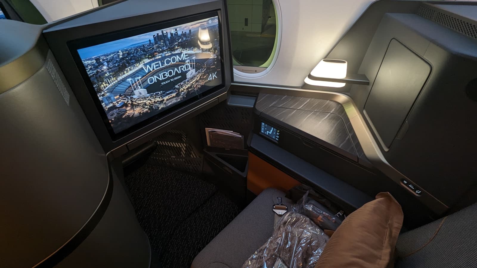 A spacious first-class airline suite with a wide seat, ottoman, and privacy console.