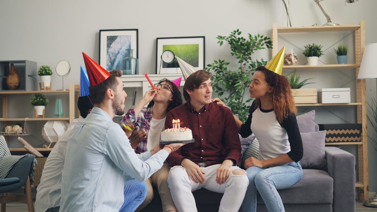 A group of friends sitting together on a couch with a cake, celebrating at home.