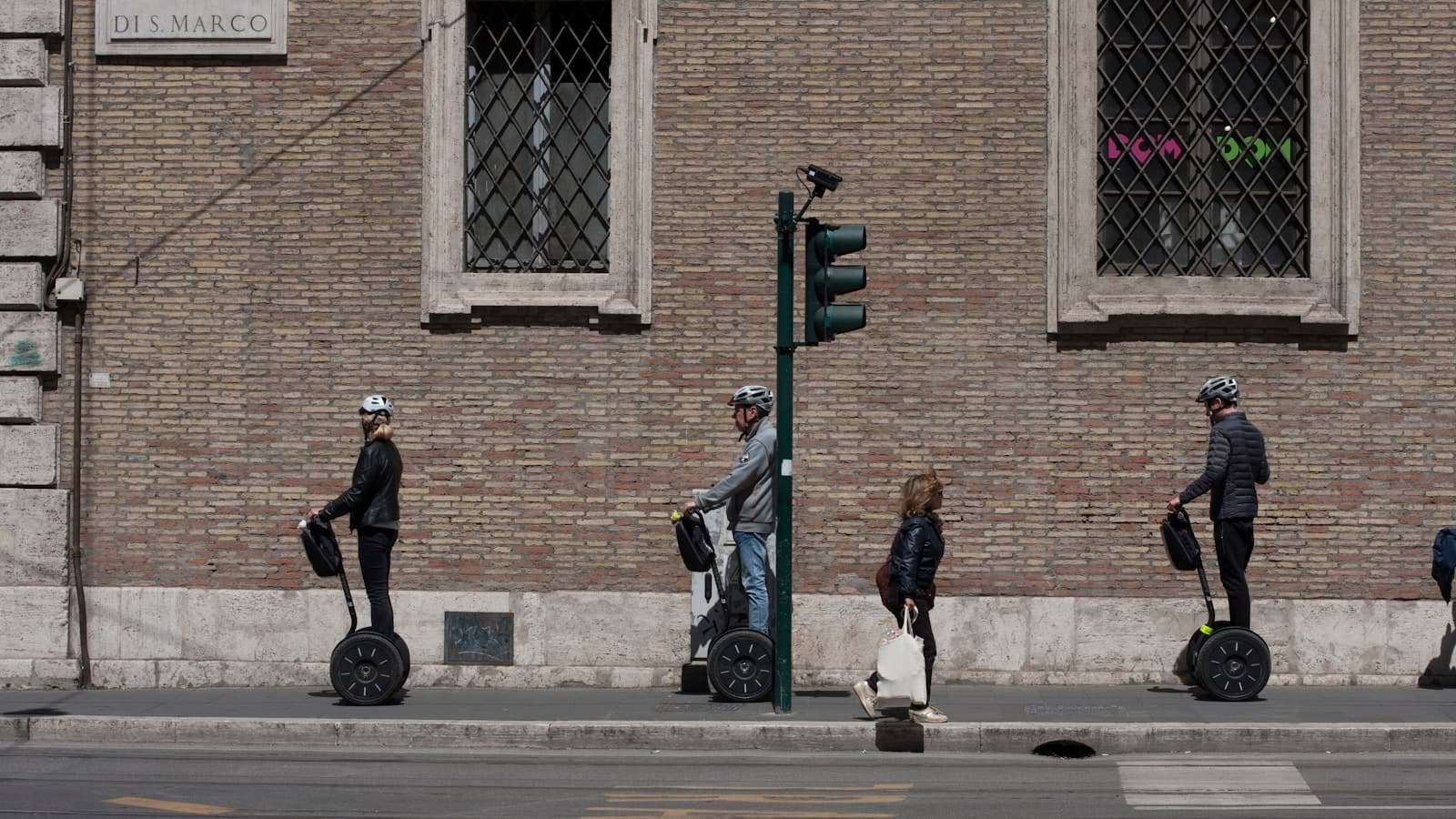 Three riders on self-balancing scooters cruising along a city street.