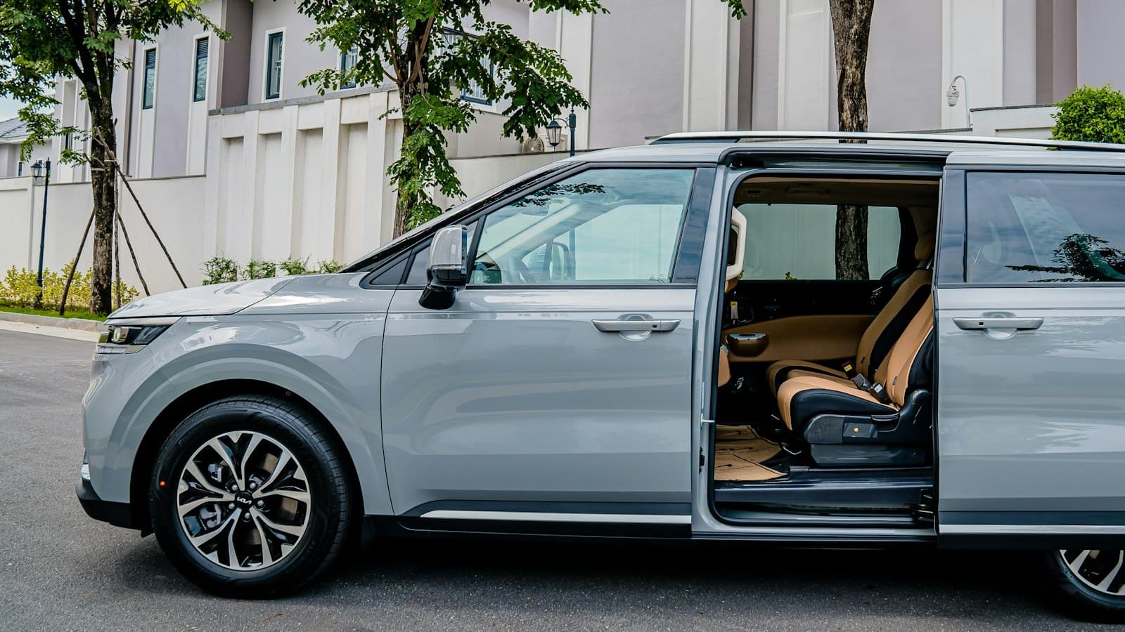 A silver minivan with its sliding door open showing the passenger seats, parked on a residential street with no visible plate, logo, or people.