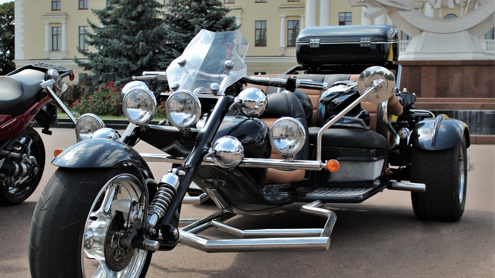 A black custom trike with chrome details parked outdoors, low-angle shot.