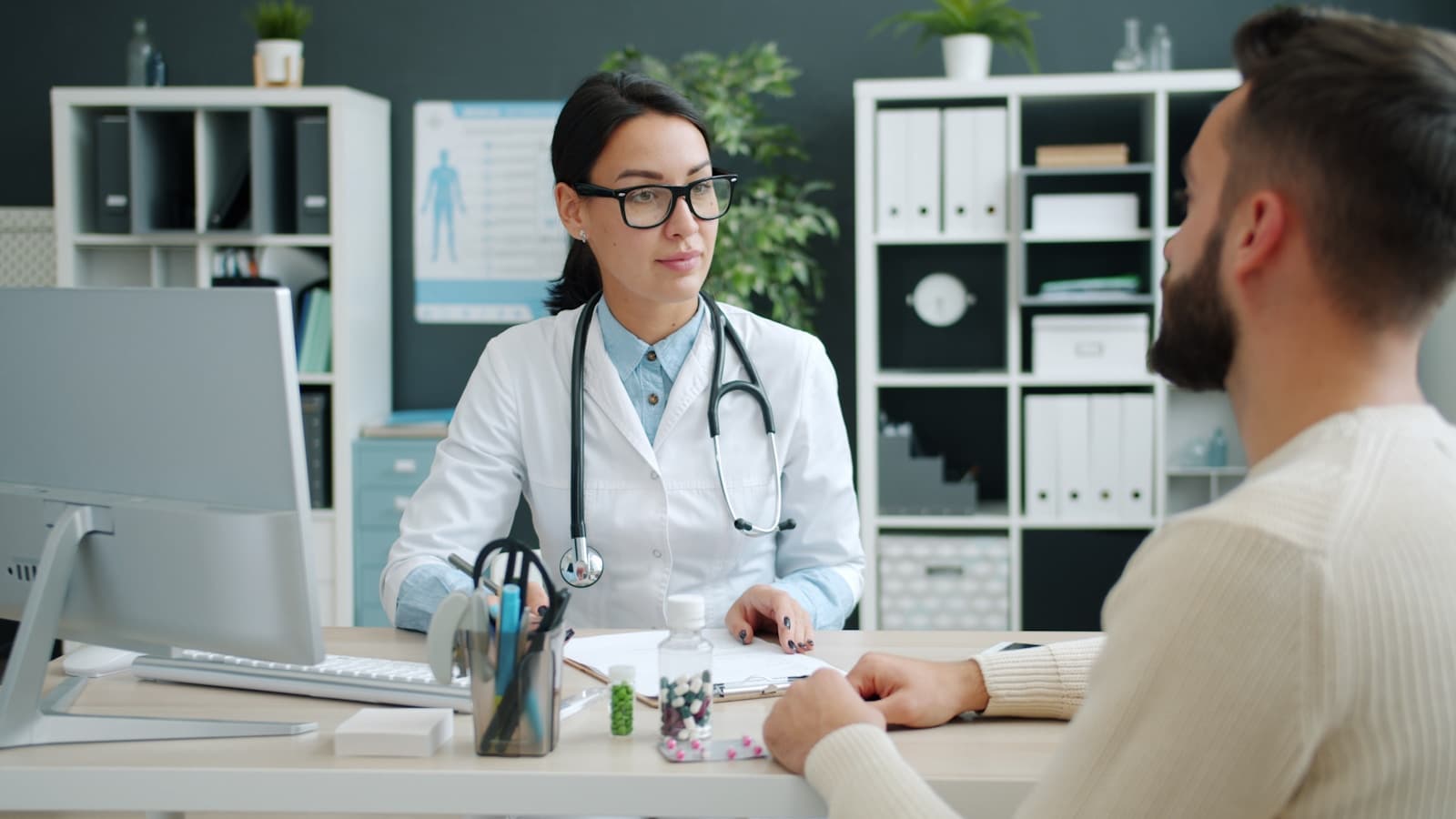 A clinician with a stethoscope consulting a patient in a bright modern office.