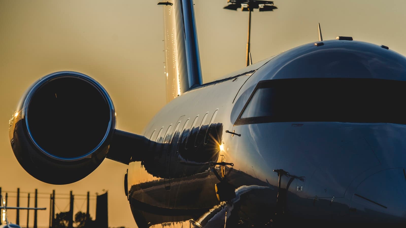 A close-up of a private jet's nose and engine glinting at sunset; no tail number or logo visible in frame.
