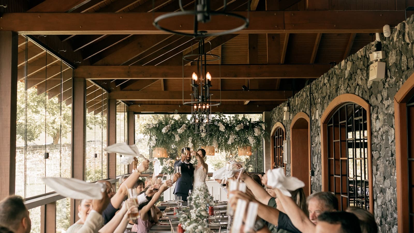 Guests toasting the happy couple at a long dinner table.