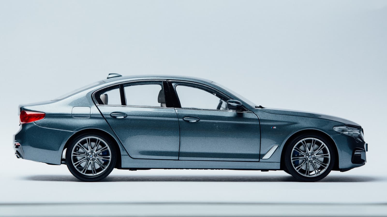 A plain gray-blue sedan shot in side profile on a neutral background, with no people, readable plate, or legible brand logo visible.
