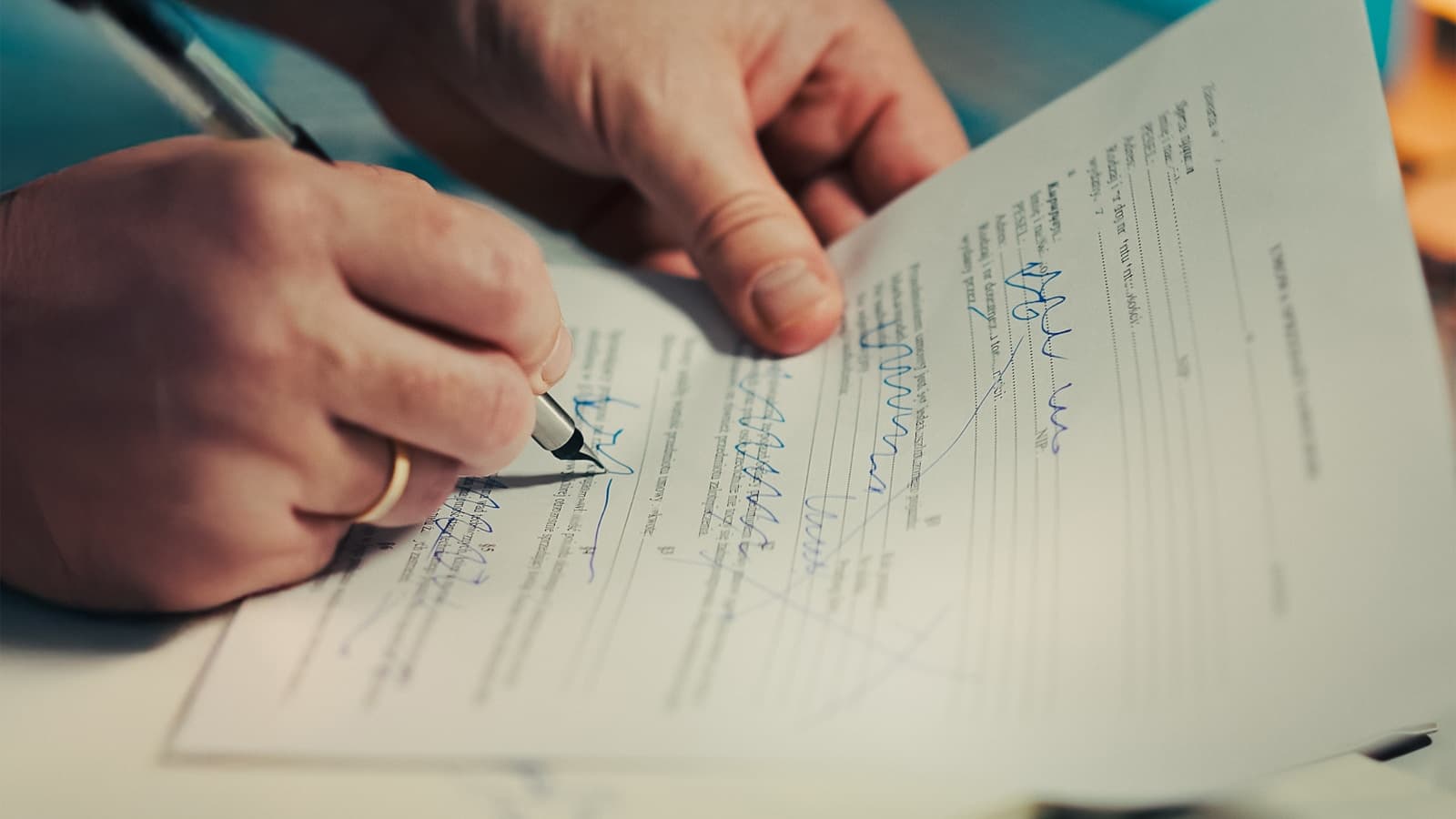 Close-up of a hand signing a form with a fountain pen.