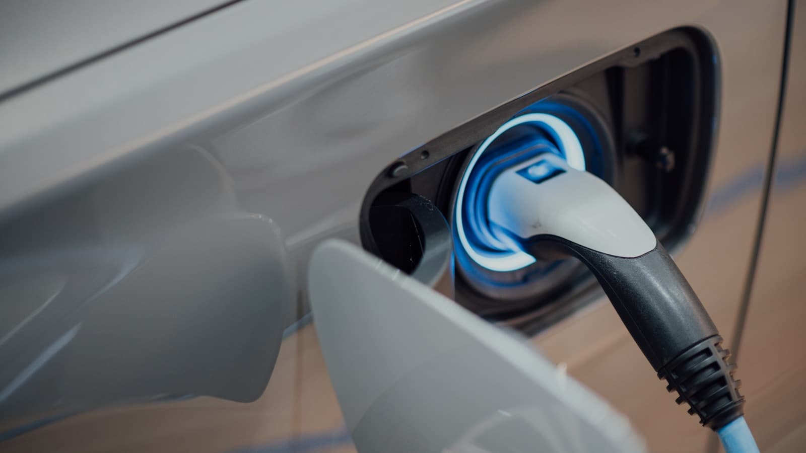 A close-up of an EV charging connector plugged into a car's port.