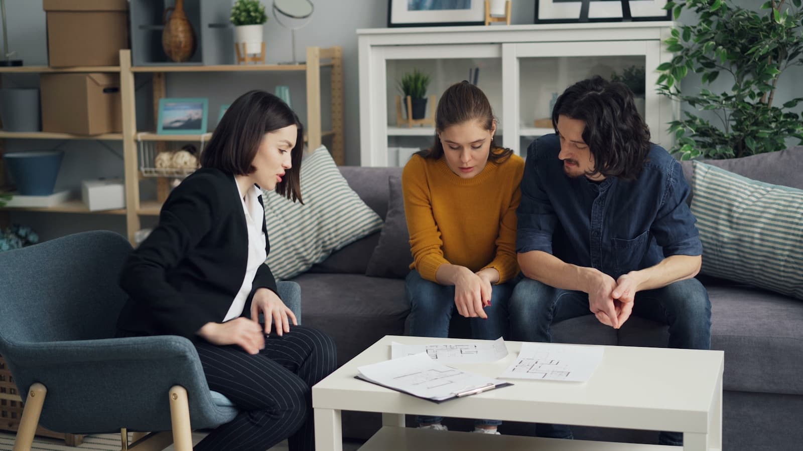 Three people reviewing a document together in a modern office lounge.