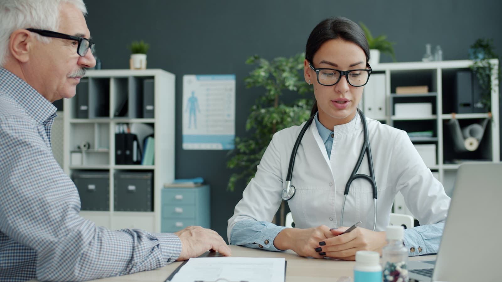 A doctor consulting with an elderly patient in a bright office.