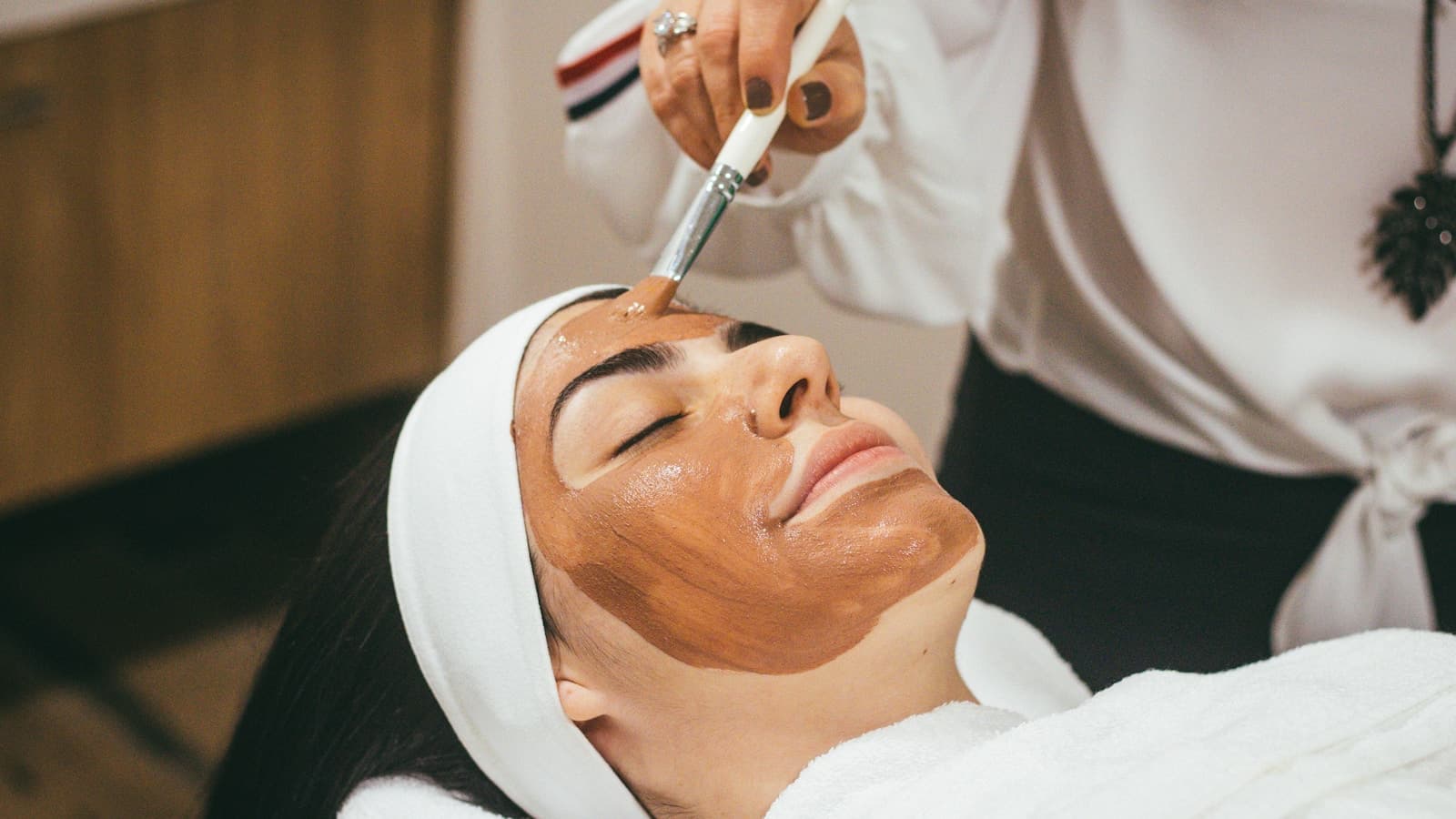 A woman receiving a facial mask treatment at a spa.