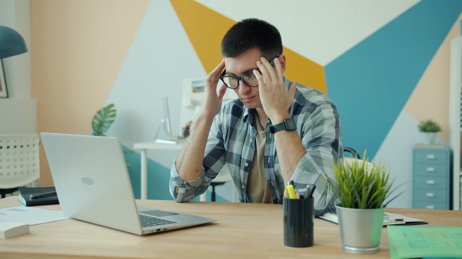 A man reviewing something intently on his laptop at a desk, serious expression.