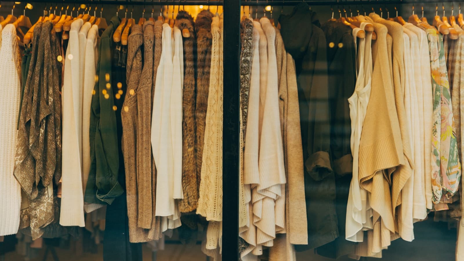 A tightly packed rack of neutral-toned sweaters and knitwear in warm light; no people, logos, or text.