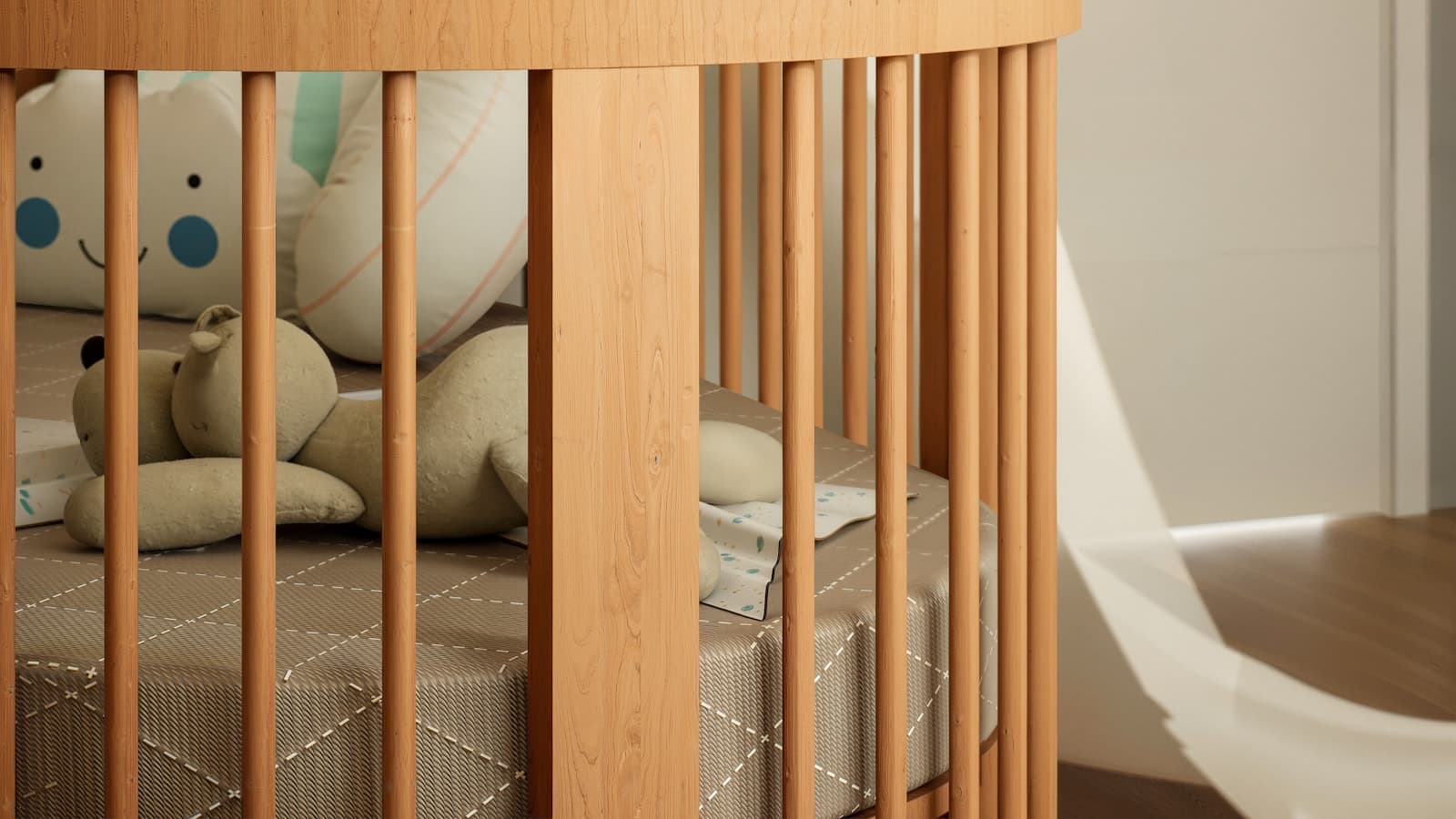 A round wooden crib with slatted sides holding two plush stuffed animals and a smiling cloud-shaped pillow.