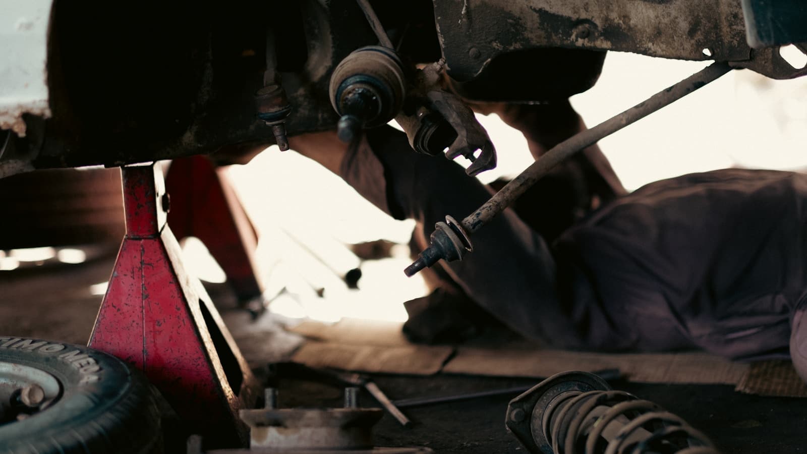 Close-up of a mechanic's hands on a vehicle's underside.