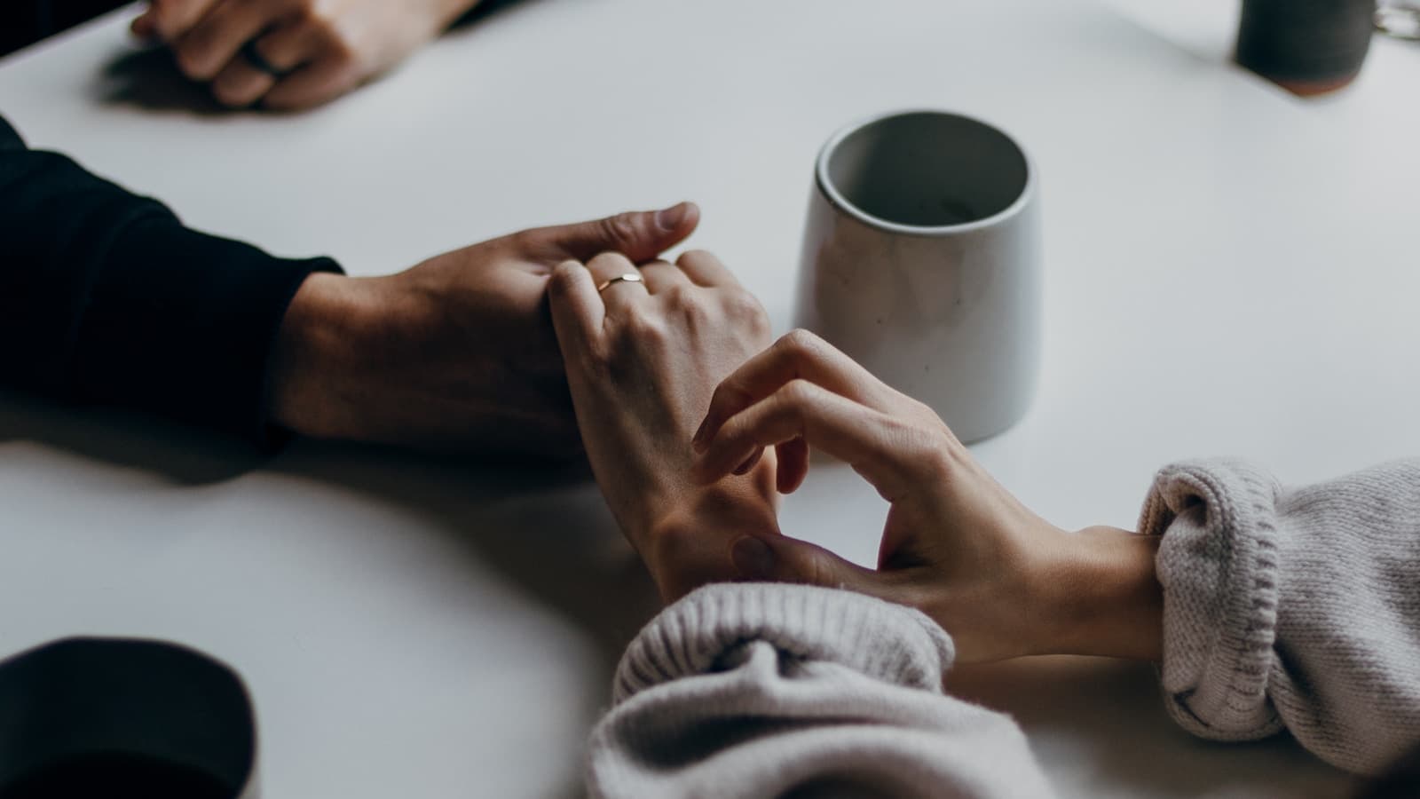 Close-up of a couple holding hands across a cafe table.