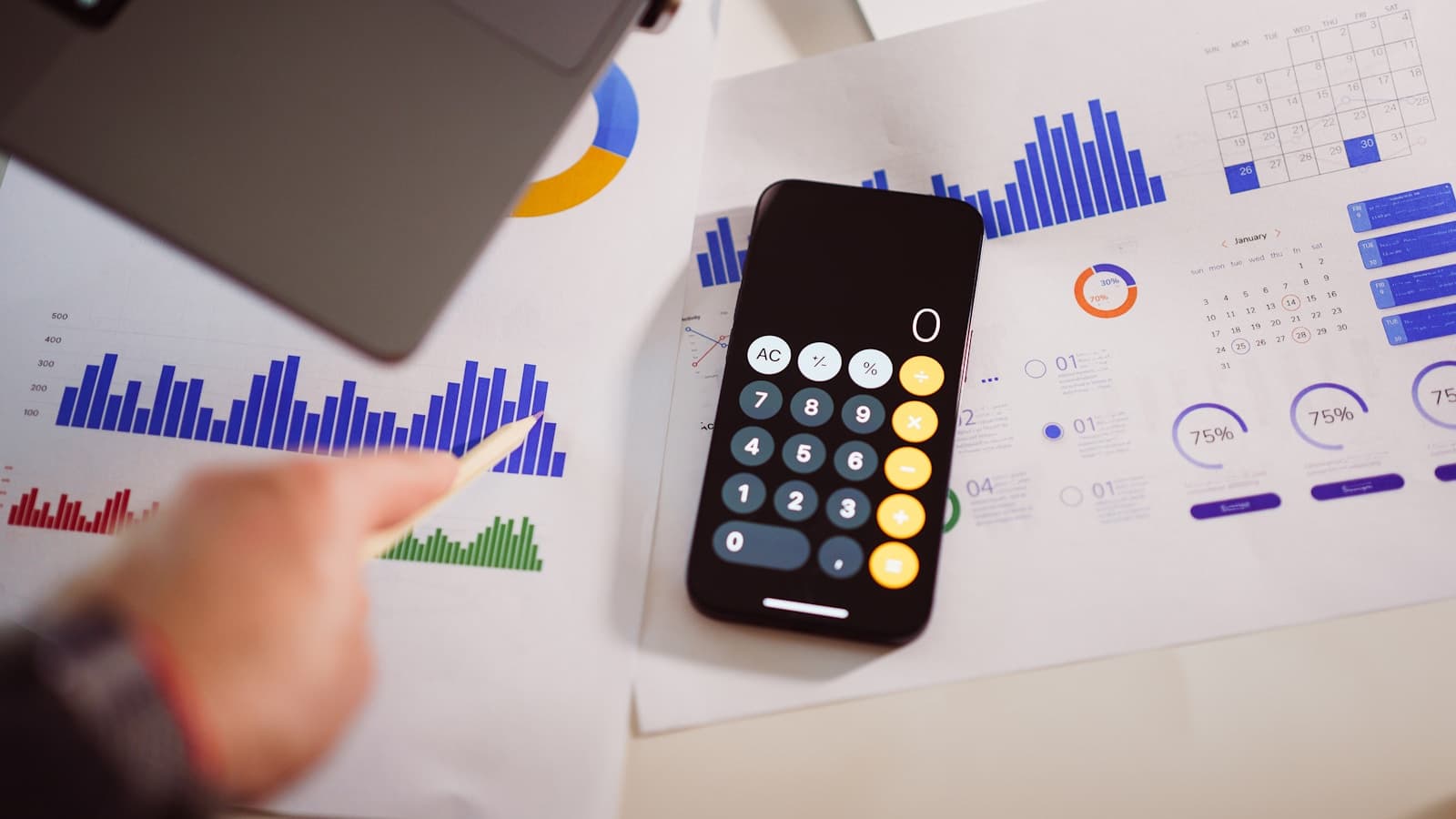 A calculator and laptop on an office table for reviewing budget and finance.
