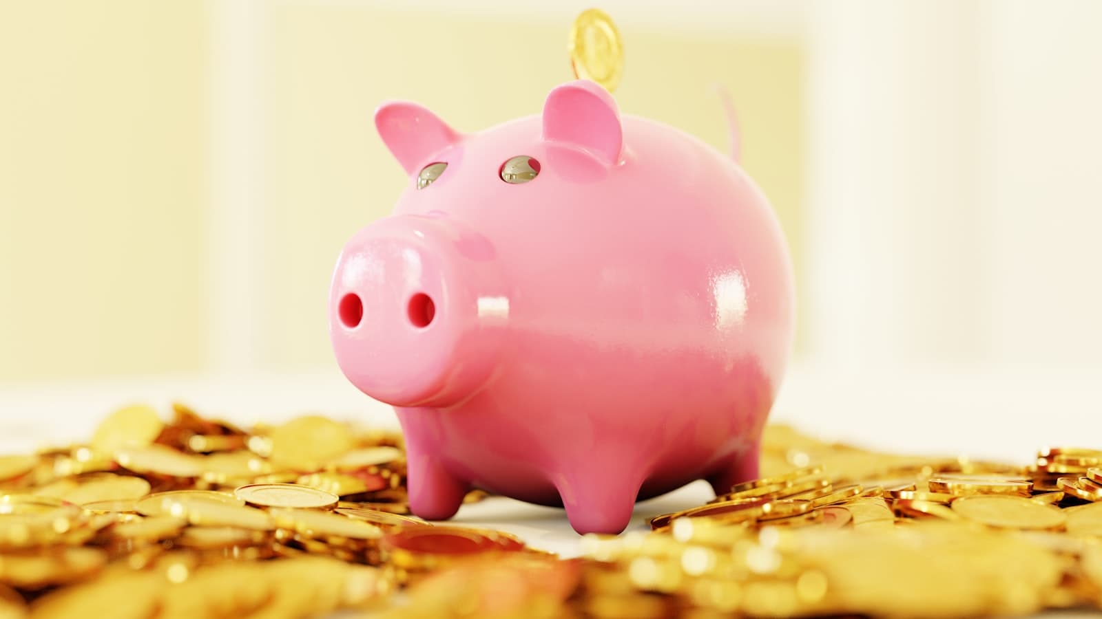 A pink piggy bank sitting on a pile of gold coins