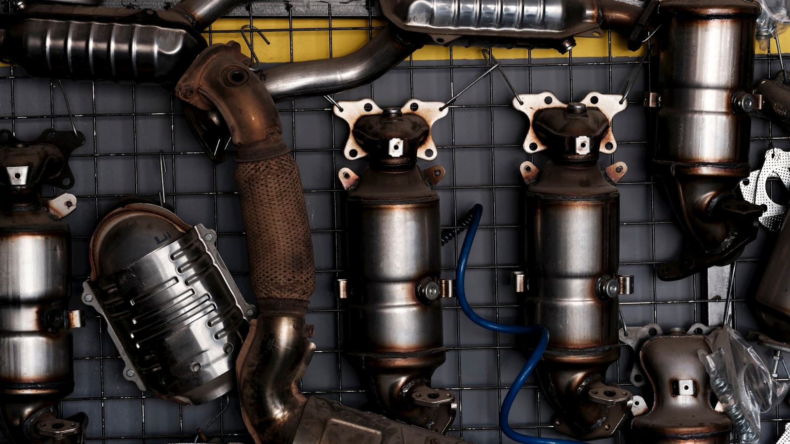 A wall of removed catalytic converters and exhaust parts, industrial close-up.