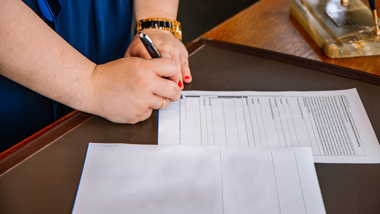A woman filling out a form at a desk.