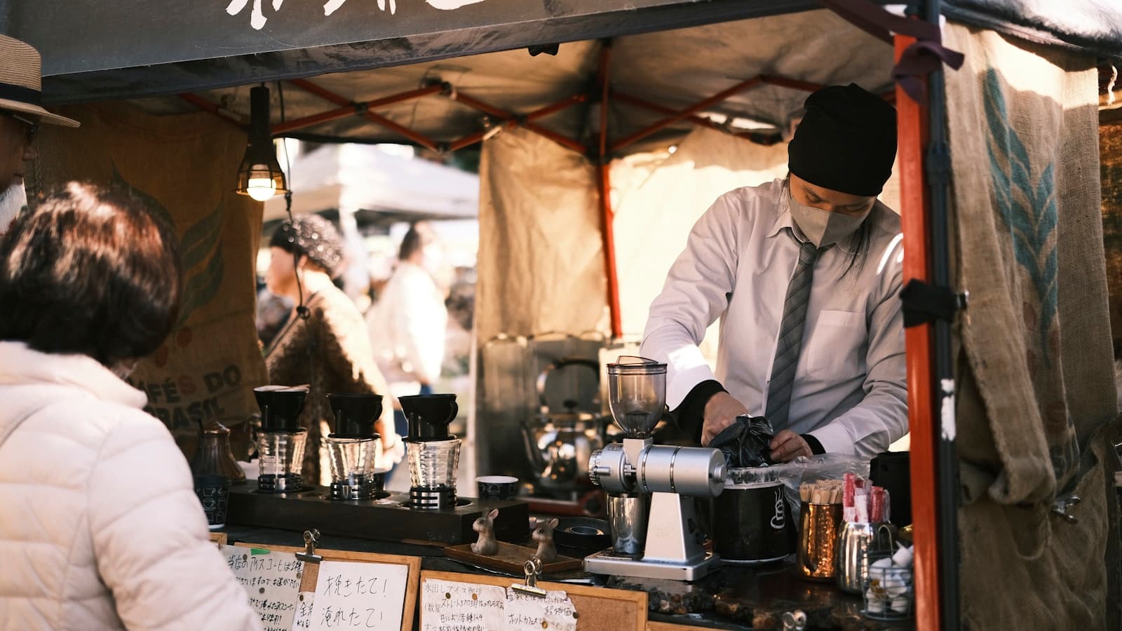 A barista working at an outdoor coffee stall.