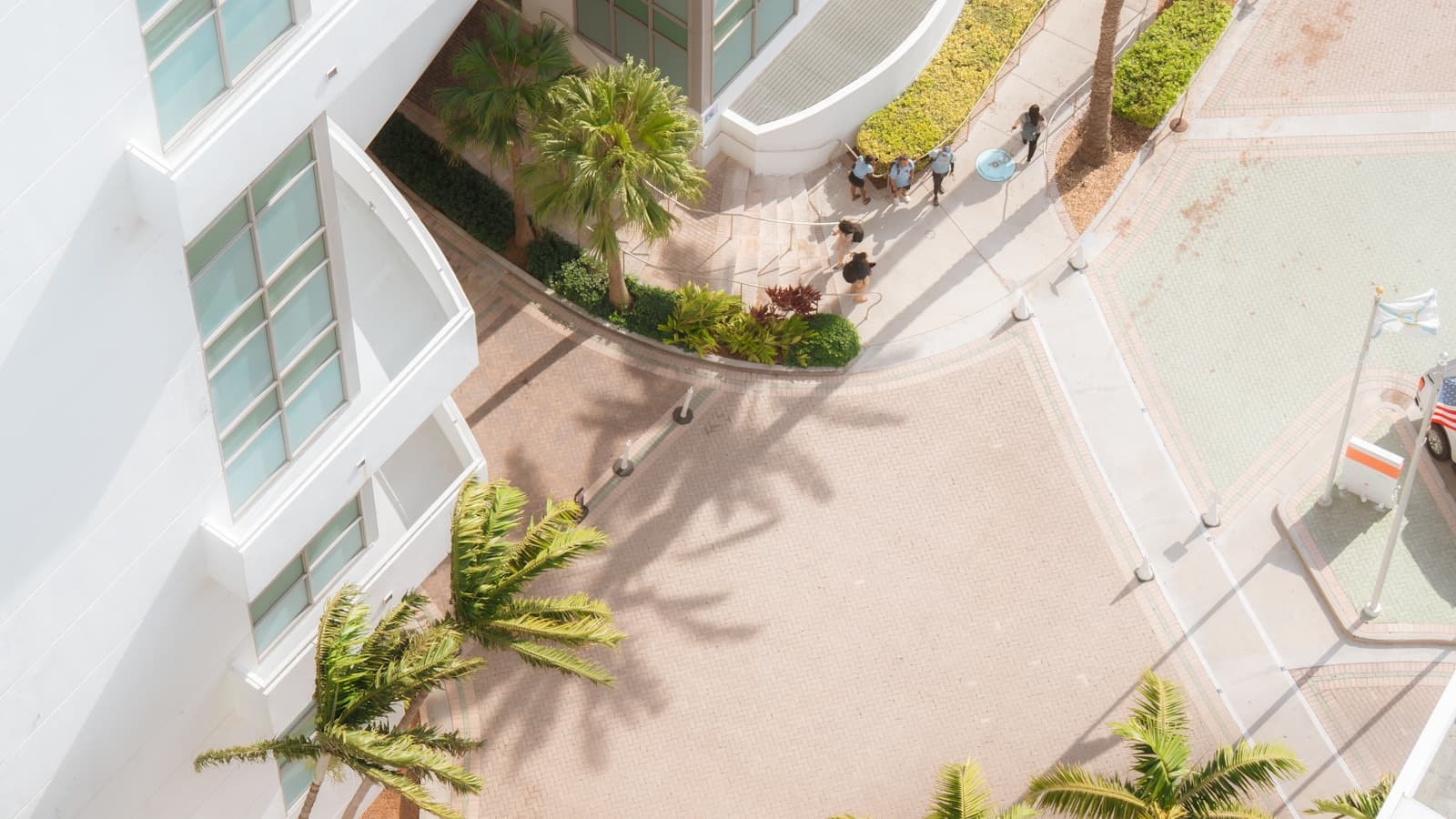 Aerial view of a modern white residential building with palm-lined walkways.