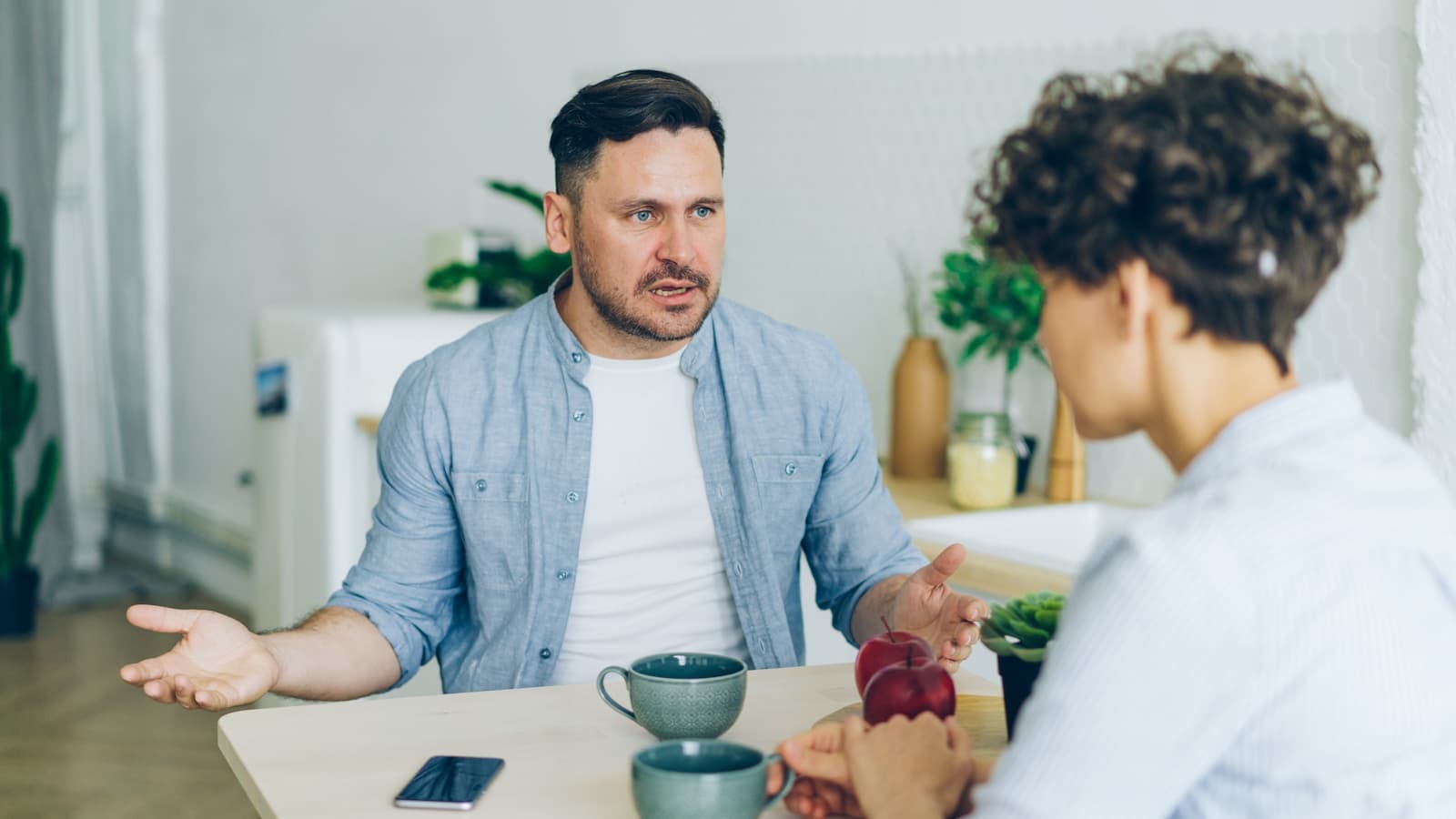 A man and woman in a serious conversation across a table.