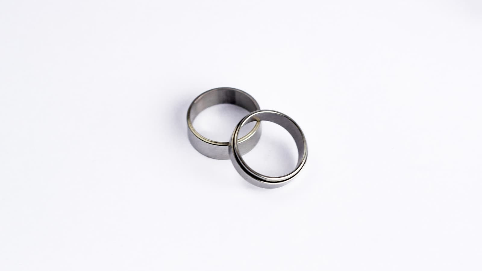 Two plain silver wedding rings resting together on a plain white surface, no text, logos, or people.