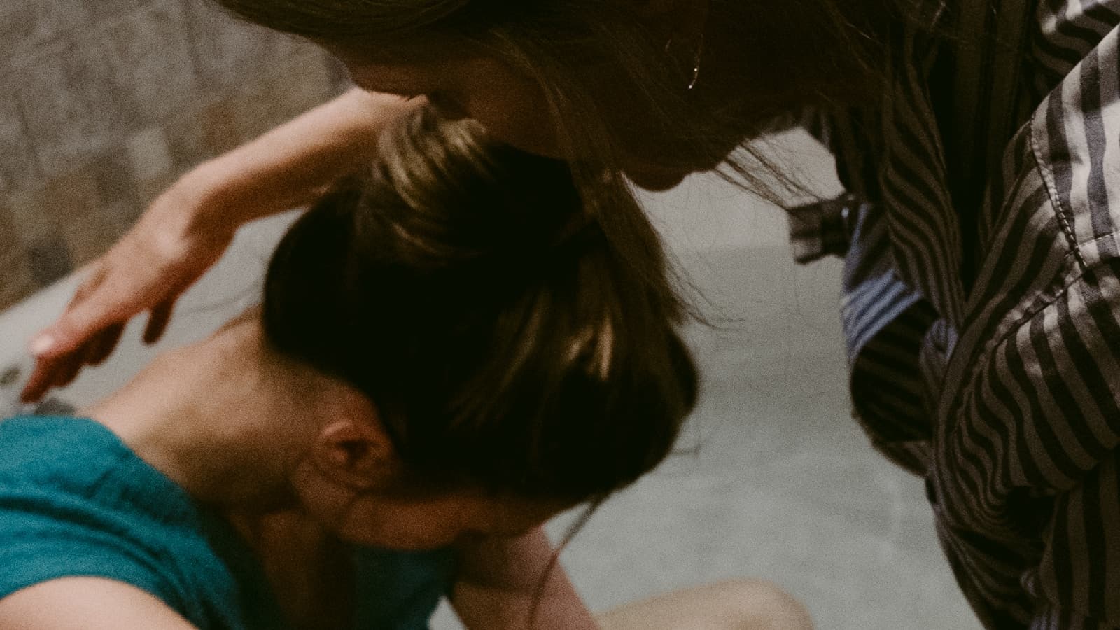 A support person comforting a laboring woman in a warmly lit bathroom, tasteful and non-graphic.
