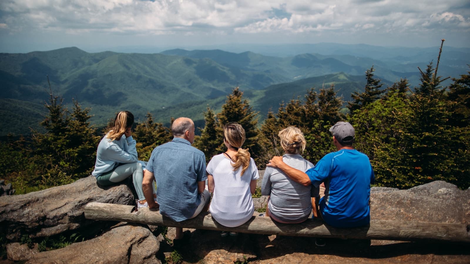 Five family members spanning multiple generations sitting together on a bench overlooking a mountain range.