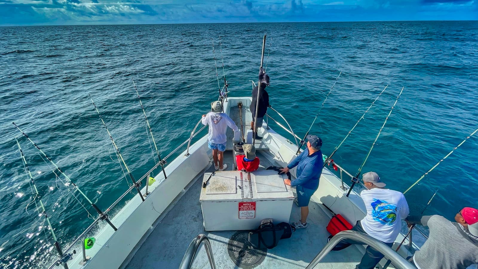 A group of people riding a charter boat during the day.