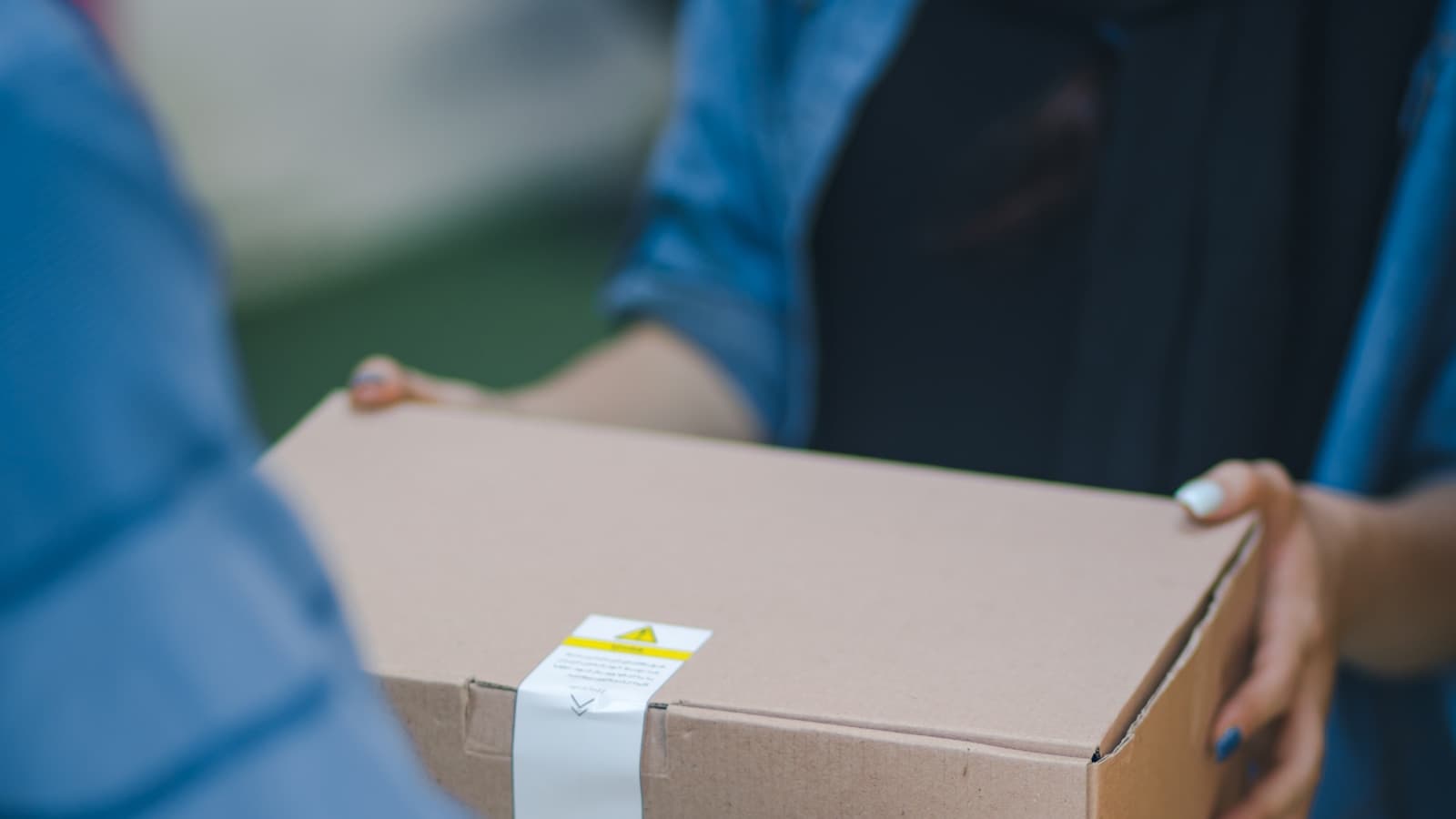 A close crop on hands, a box being handed from one person to another.
