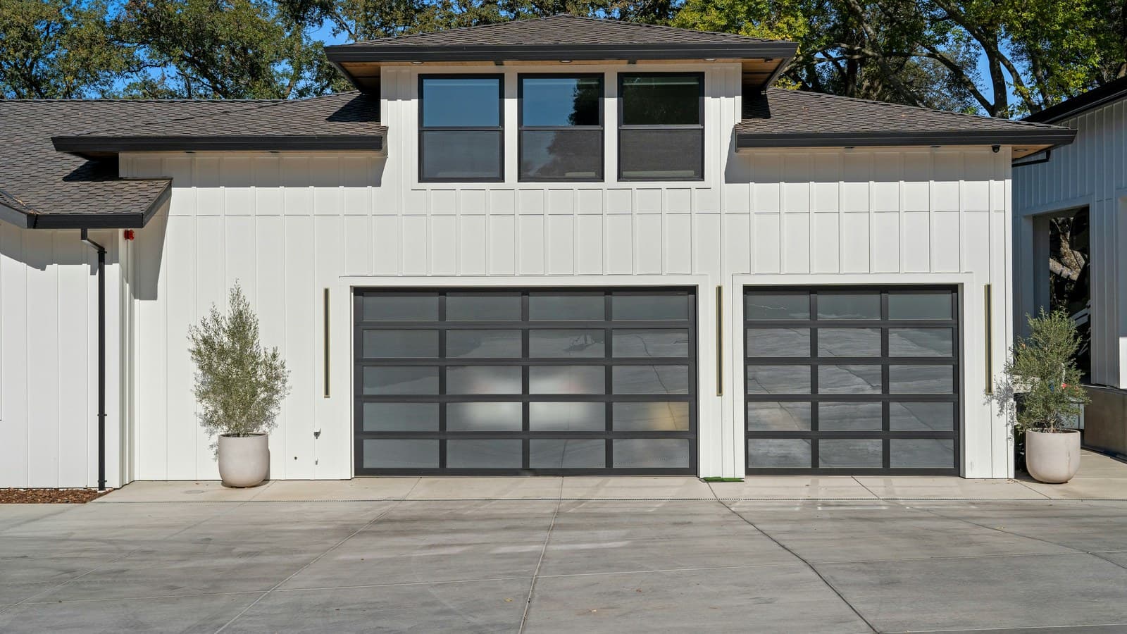 A modern white house with a clean two-car garage featuring frosted-glass paneled doors; no faces, plates, or readable text.