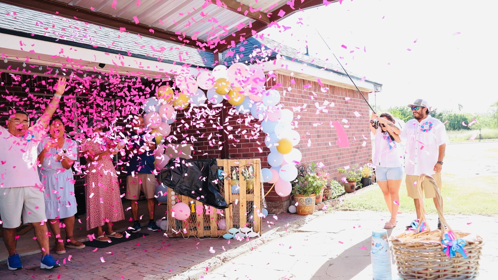 A family cheering together as pink confetti and smoke fill the air outdoors.