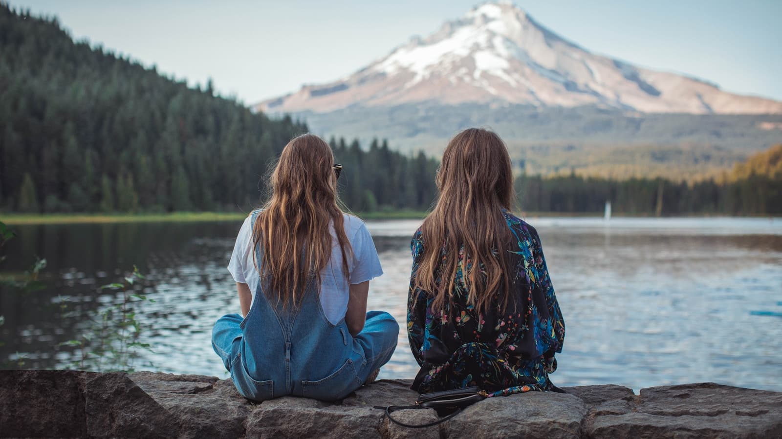 A group of women sitting together on a rock near the water.