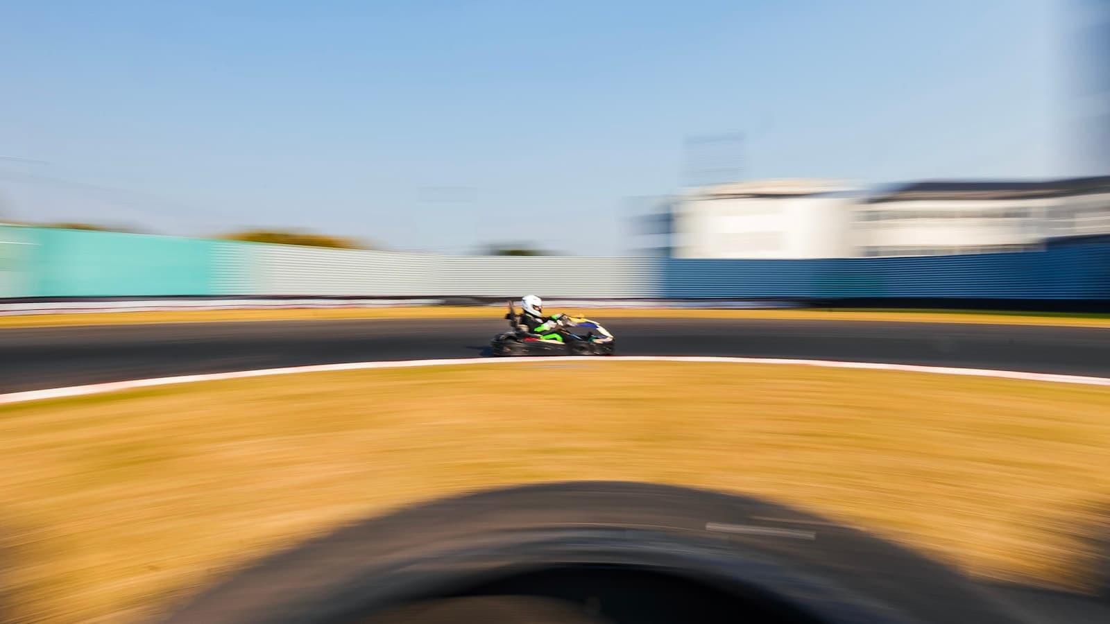 Two go-kart drivers racing closely on an outdoor track.