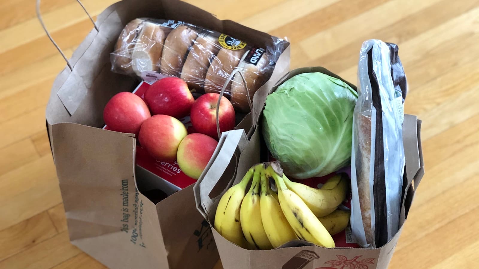 Apples and bananas packed in a brown cardboard delivery box.