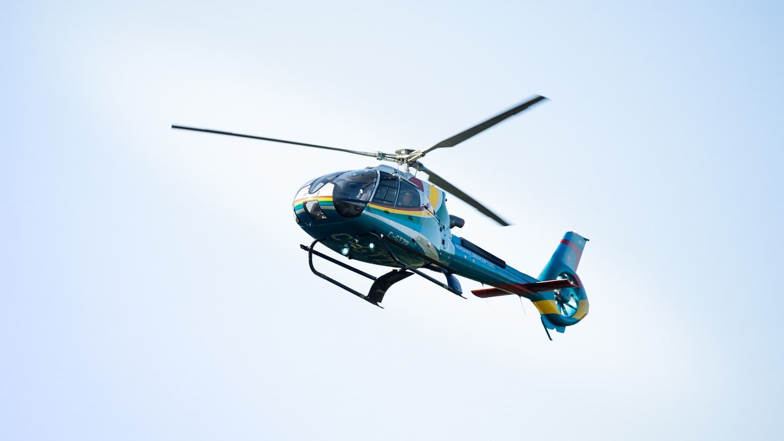 A colorful helicopter in flight against a clear sky.