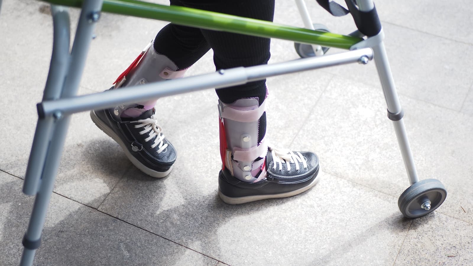 A person standing next to a walker indoors, mobility-aid recovery scene.