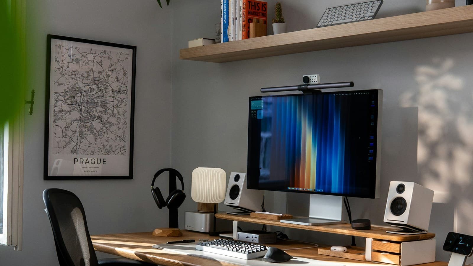 A modern home office with a wooden desk, monitor, keyboard, bookshelf, and desk chair.