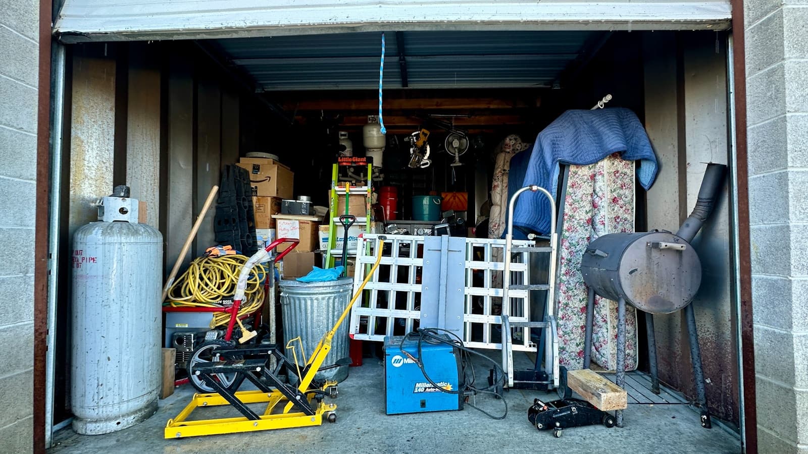 An open garage packed with tools, ladders, and clutter ready to be hauled away.