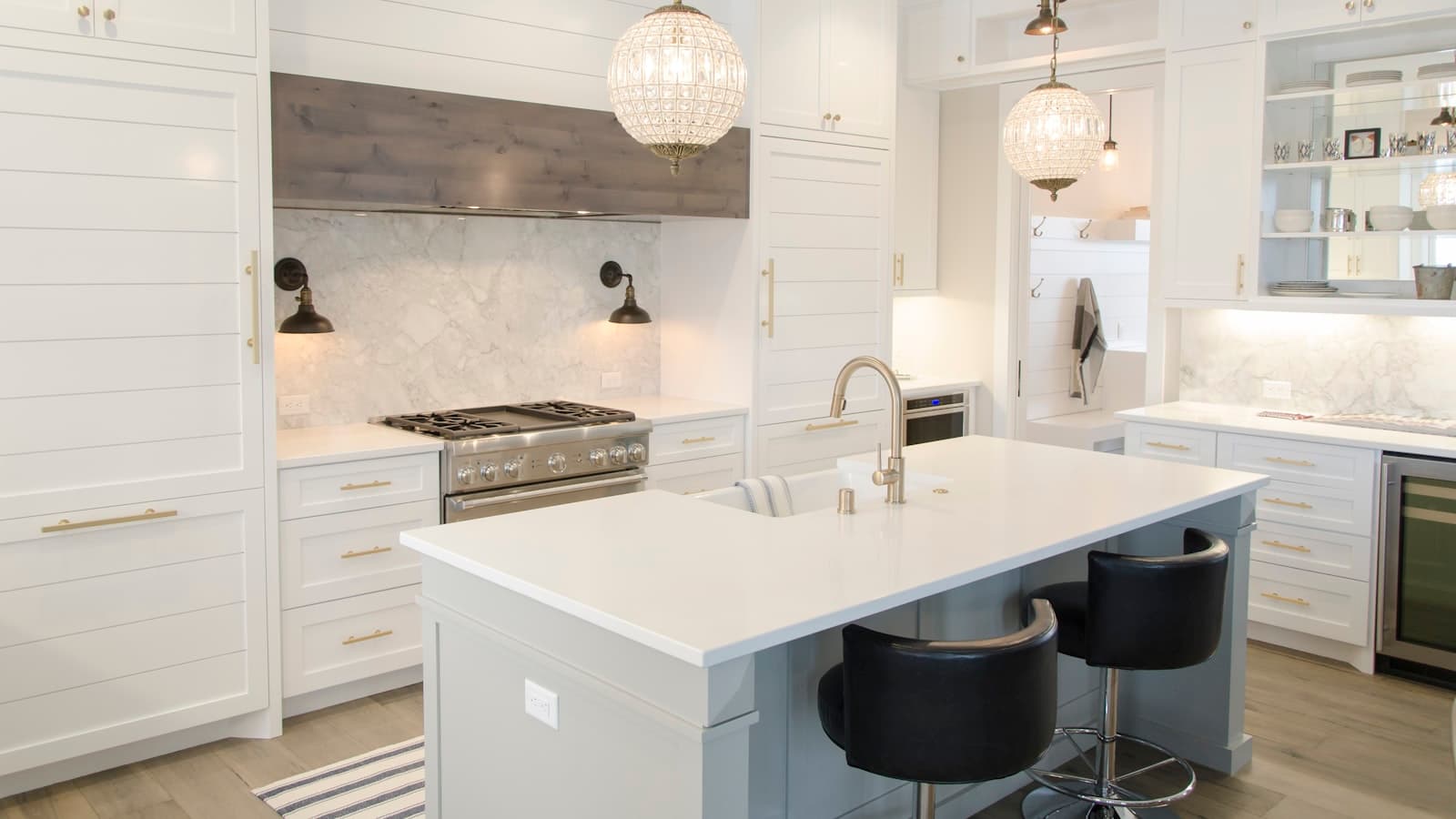 A bright white remodeled kitchen with an island, pendant lights, and stainless range, no people or readable branding visible.