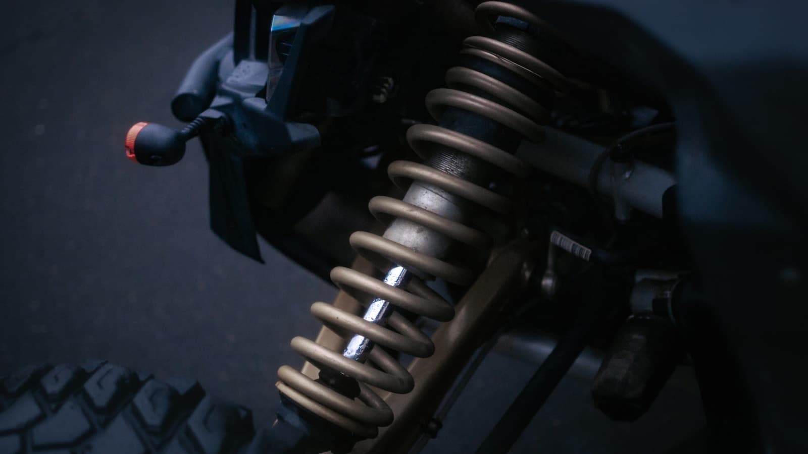 Close-up of a raised off-road vehicle's coil-over shock absorber, spring, and knobby tire.