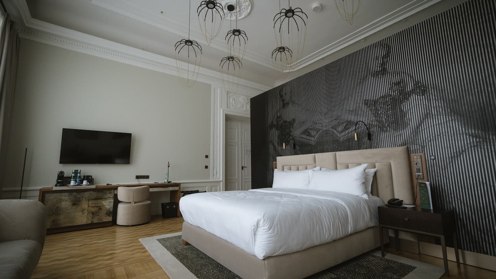 A modern hotel bedroom with a tall bed, statement accent wall, and clean styling.