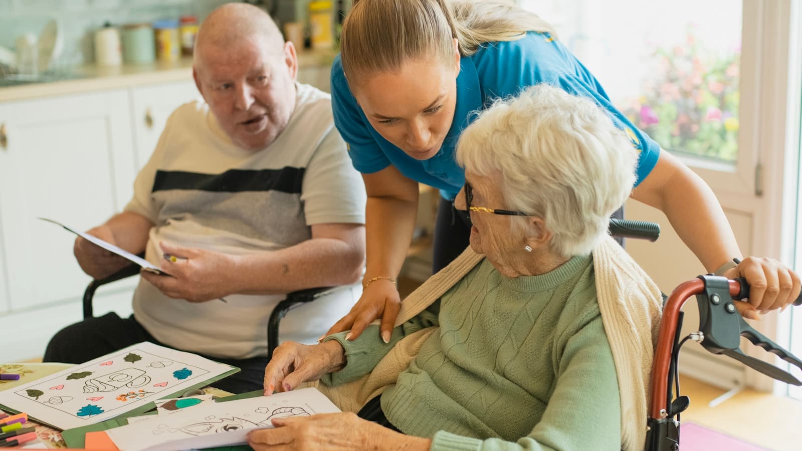 A home caregiver helping an elderly man and woman look through activities together.
