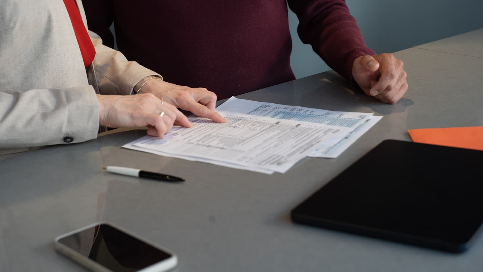 Two professionals reviewing a paper document together at a conference table.