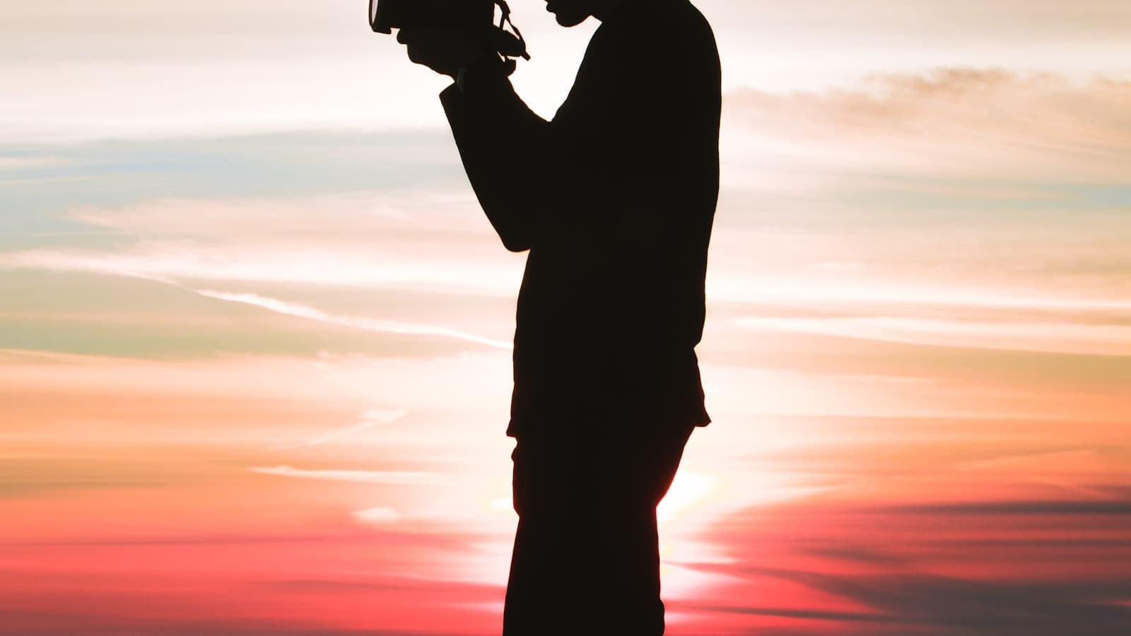 Silhouette of a man holding a camera up to shoot.
