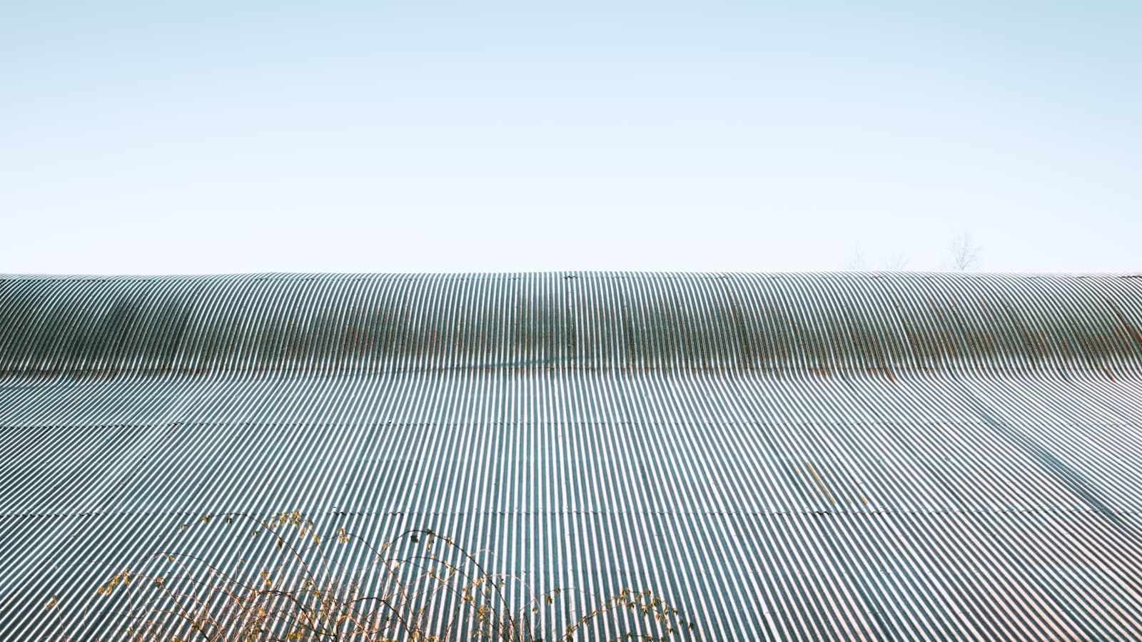 A clean corrugated metal roofline against a clear blue sky.