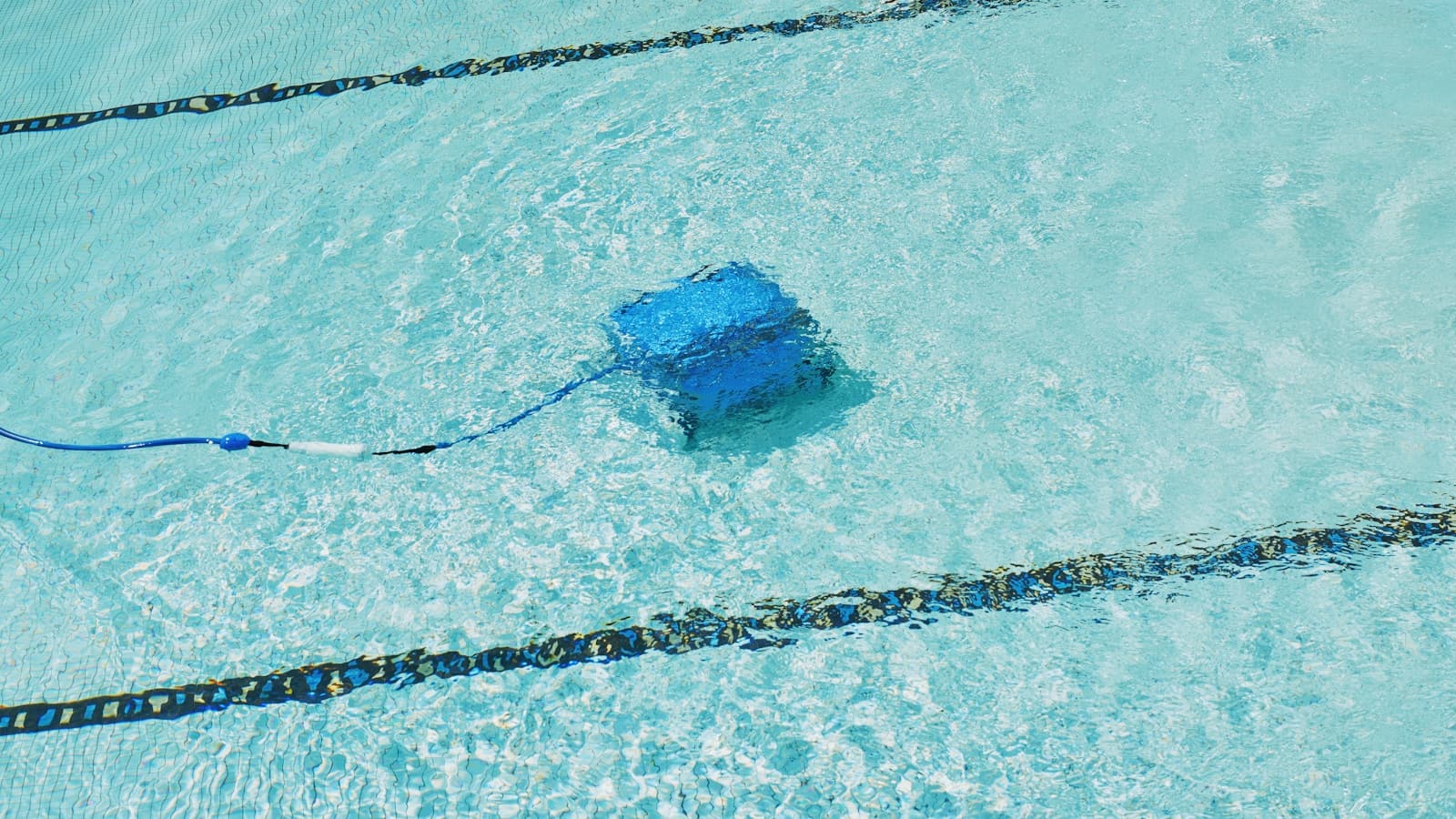 A robotic pool cleaner working underwater in a residential pool.