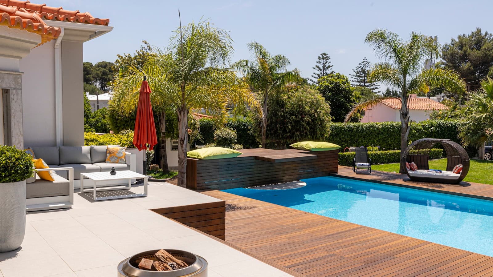 A backyard pool with a pool house and lounge seating area next to it.